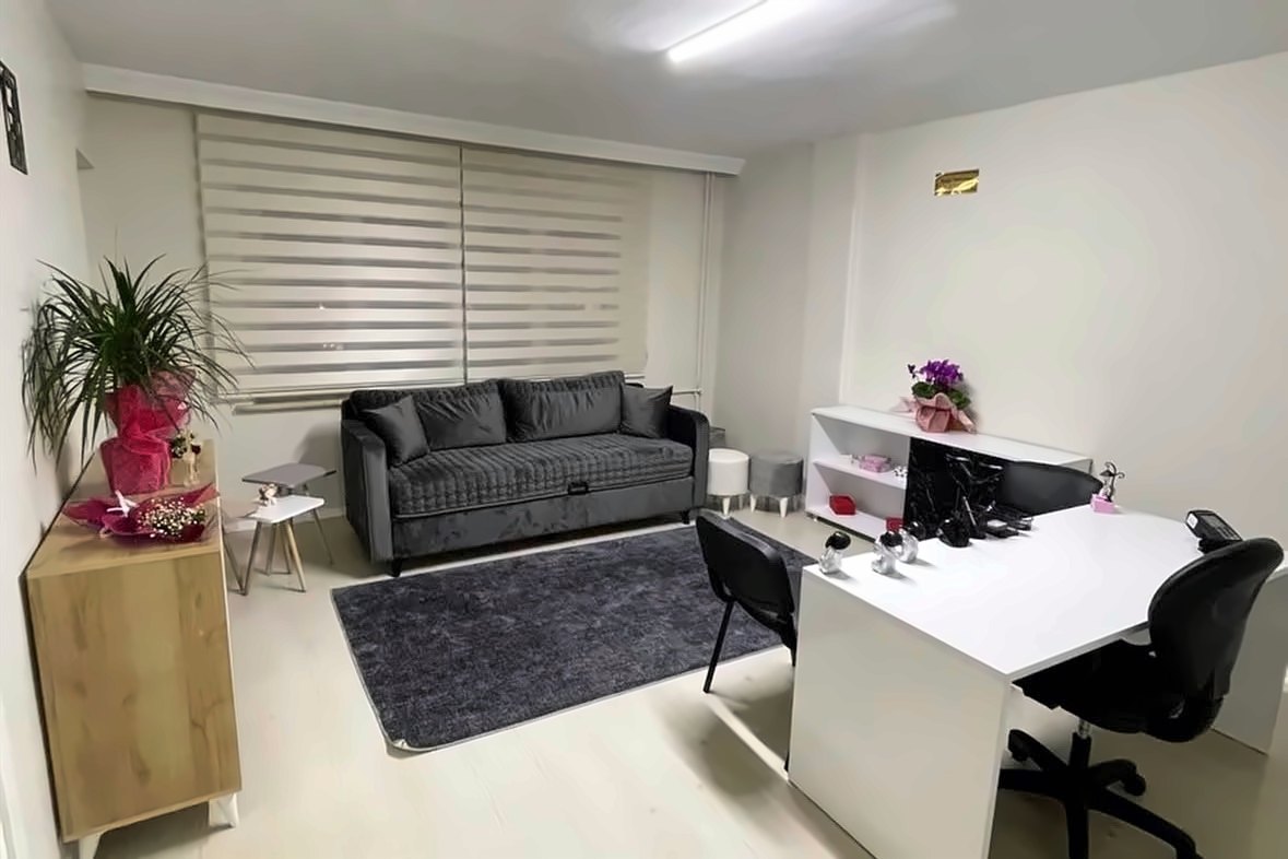 Bekleme alanı: koltuk, resepsiyon masası ve bitkiler